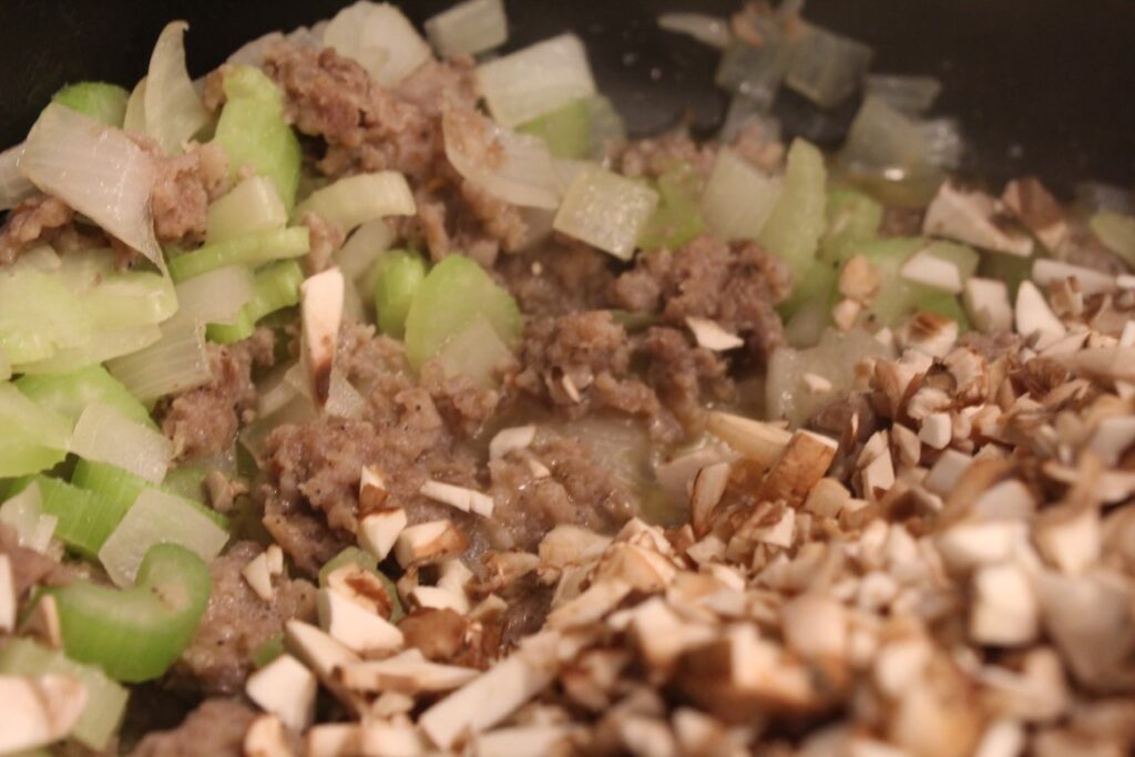 Adding minced mushrooms to browned sausage with onions and celery.