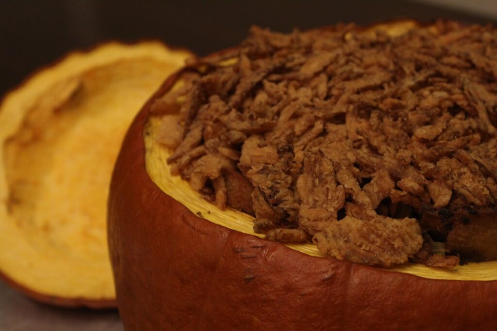 Thanksgiving stuffing casserole in a pumpkin topped with fried onions. 