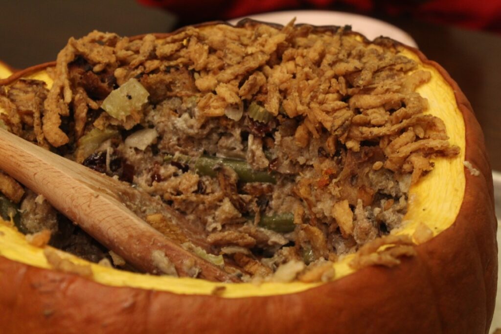 Serving thanksgiving stuffing casserole out of a pumpkin.