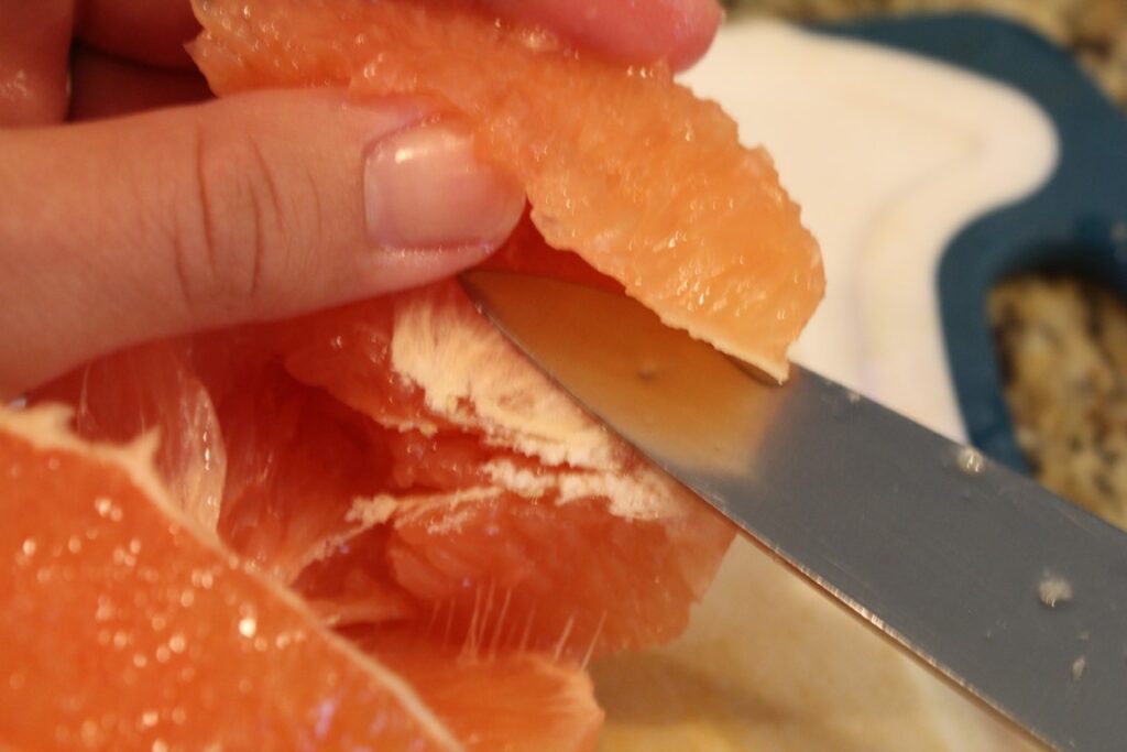 Using a knife to cut out a wedge of grape fruit.