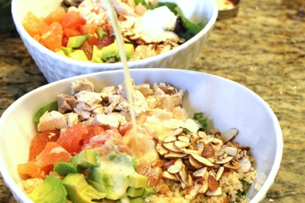 pouring lemon yogurt dressing onto grapefruit salad.