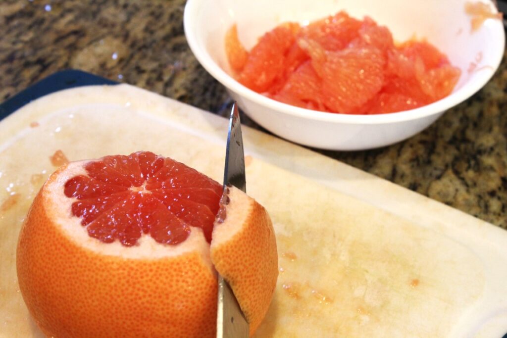 Knife cutting the peal off of a grapefruit.