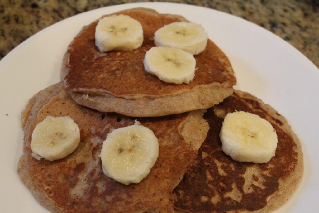 Three Whole wheat banana pancakes topped with banana slices.