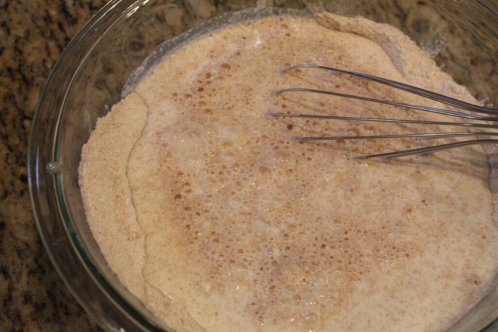 mixing milk into flour mixture with a whisk.