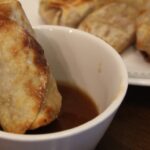 Air fried egg roll dipped in sauce.