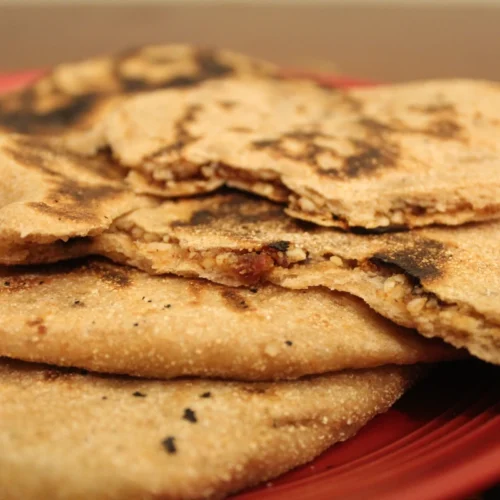 Stack of Sourdough sweet naan the top piece ripped in half to see filling.