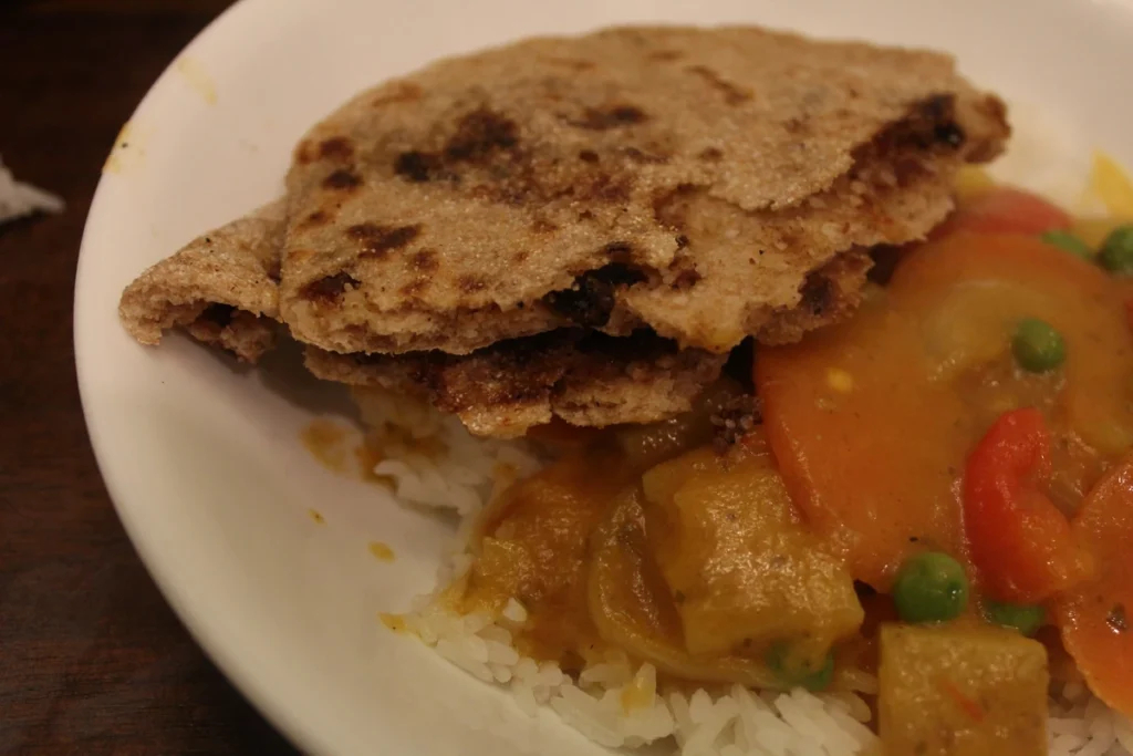 broken pieces of sourdough sweet naan in a bowl of curry.