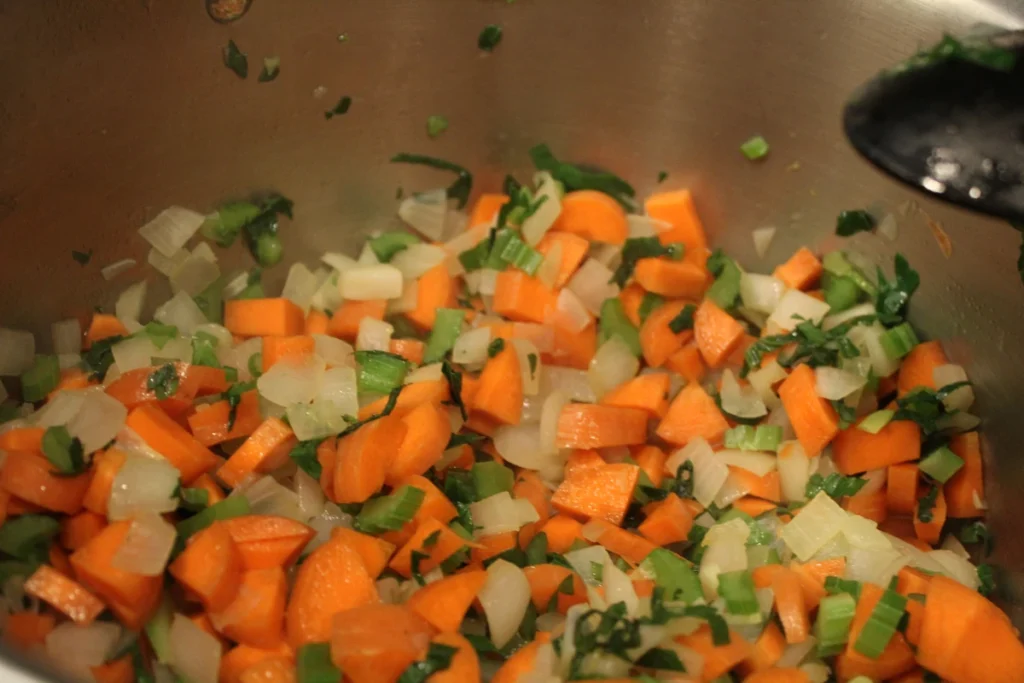 carrots onions and celery sauteing in a pan.