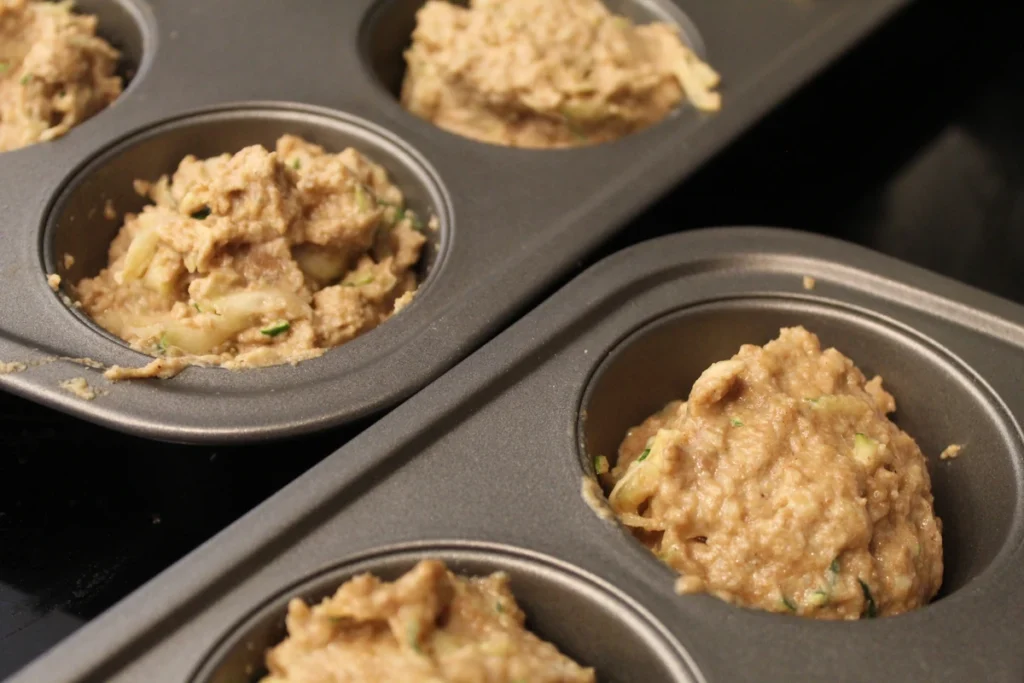 Zucchini apple sauce muffing batter scooped into a muffin tin.