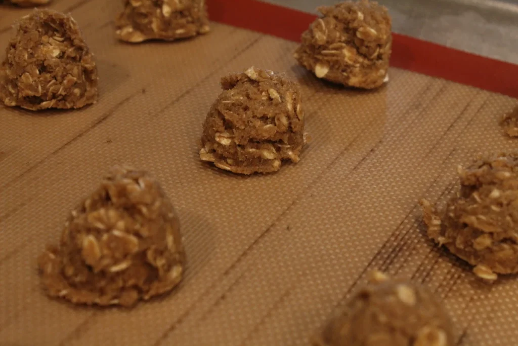Pumpkin spice oat cookie dough scooped onto a baking sheet.