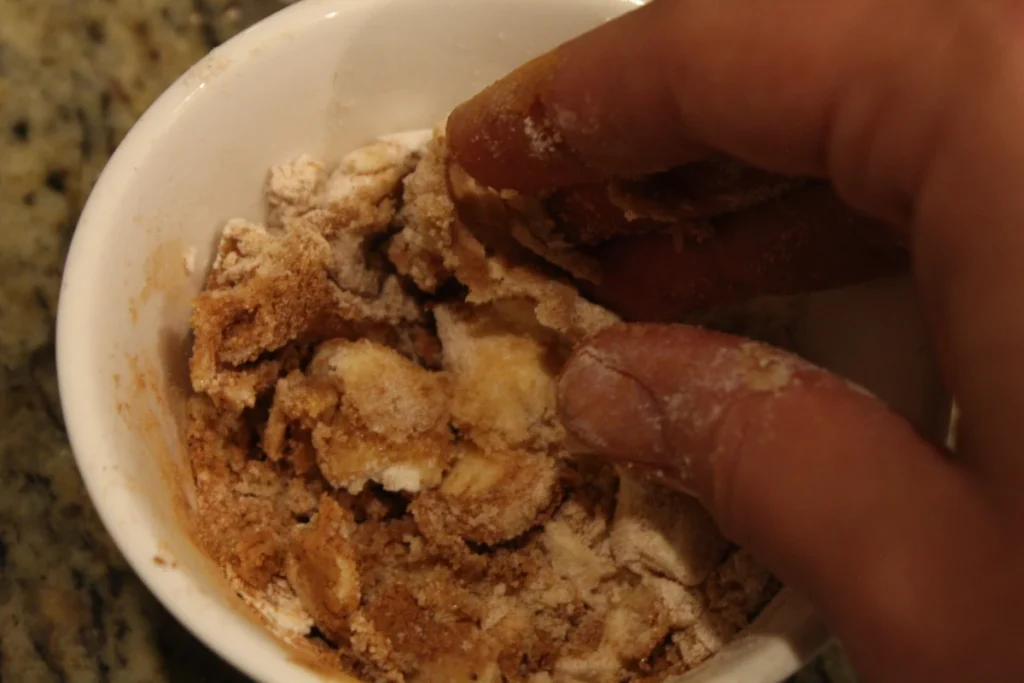 Mixing butter sugar flour and spices in with fingers.