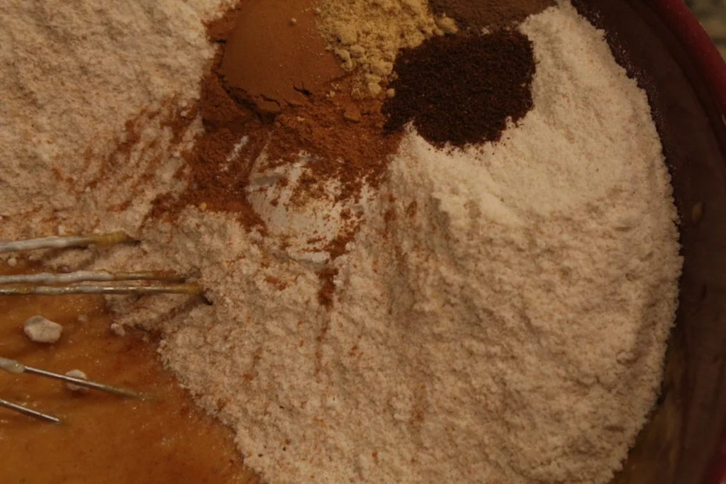 Mixed wet ingredients topped with whole wheat flour and spices.