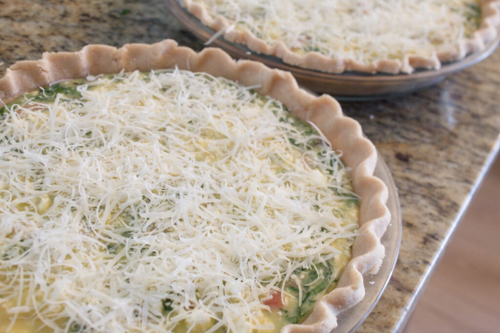unbaked quiche topped with freshly grated parmesan cheese.
